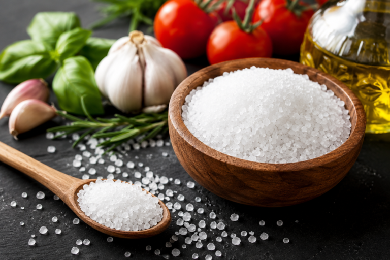 Coarse salt in a wooden bowl with fresh ingredients