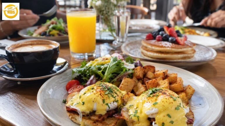 Eggs Benedict with crispy potatoes, coffee, orange juice and pancakes at a brunch table